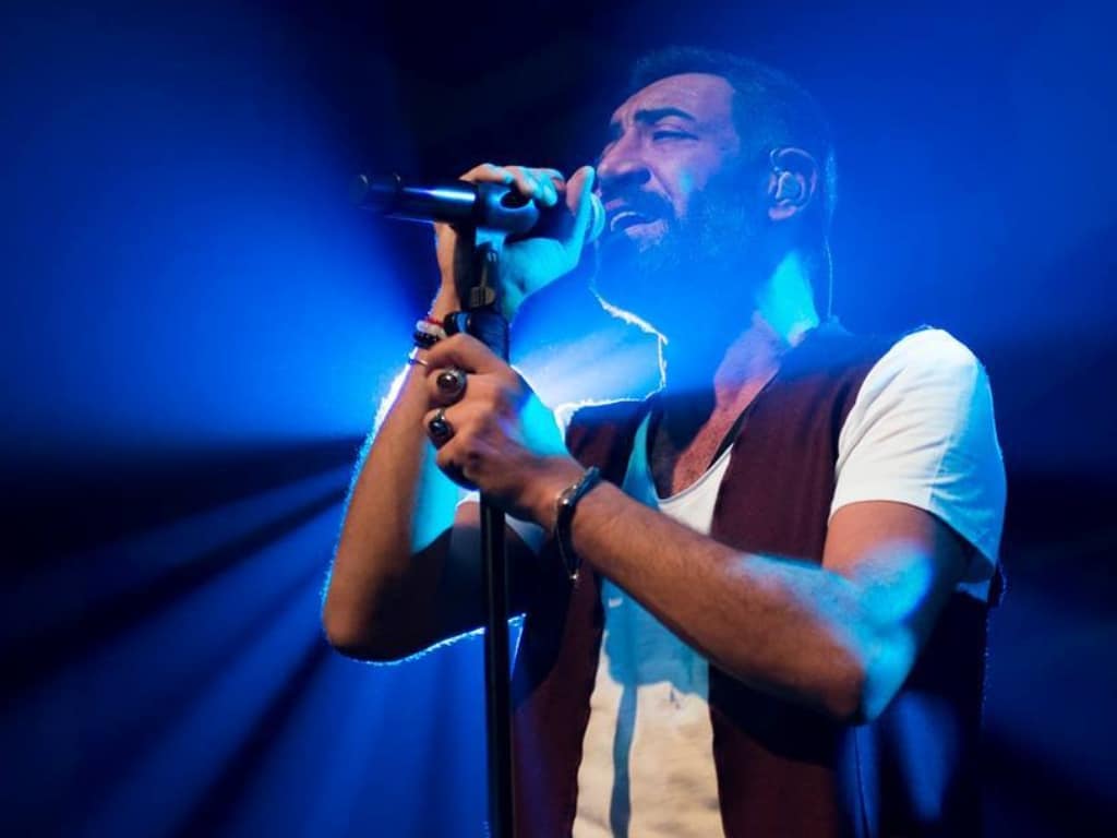 Hakan Altun mavi ışığın önünde sahnede şarkı söylüyor